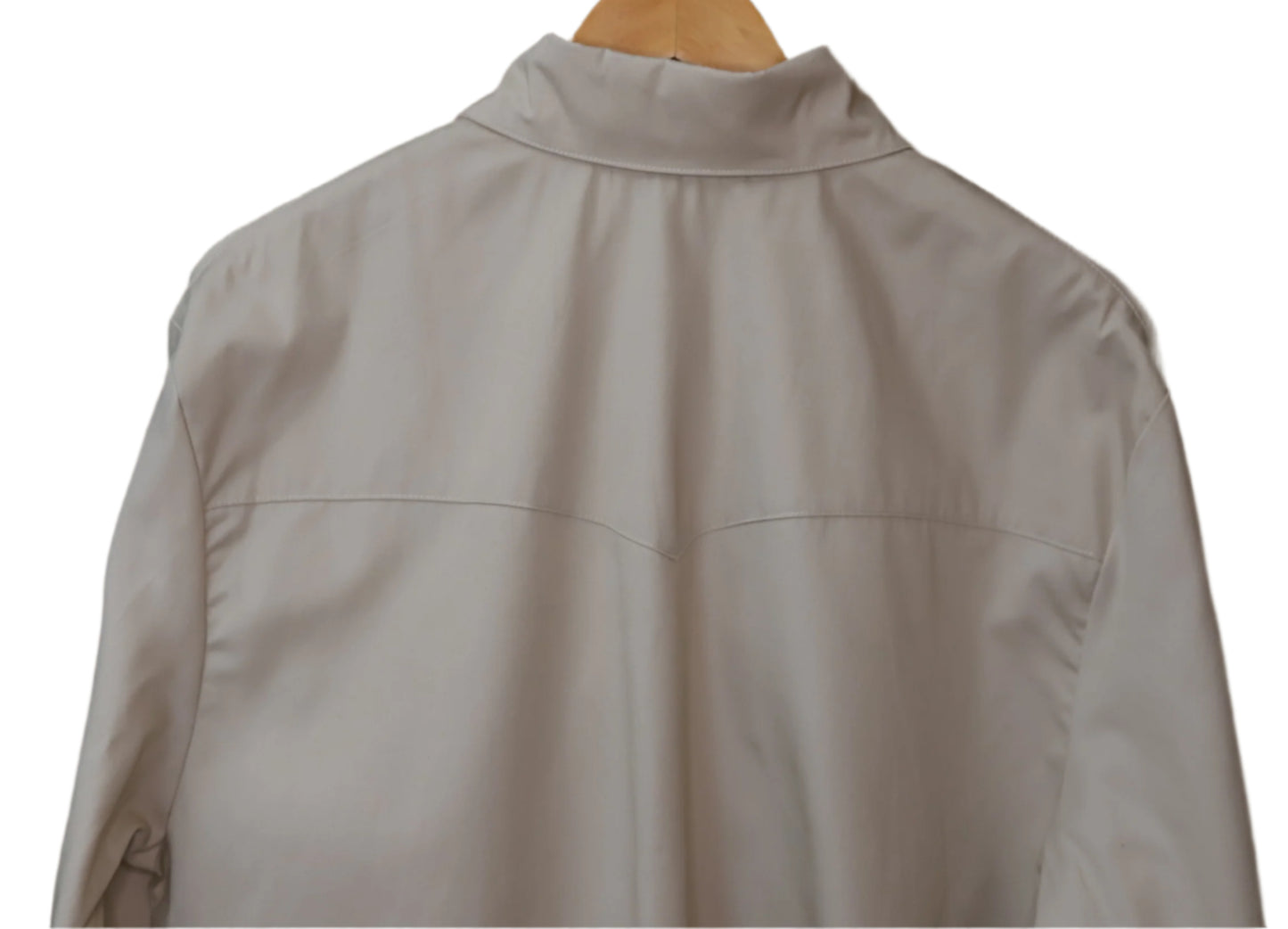 Light gray jacket on a wooden hanger against a brown wall