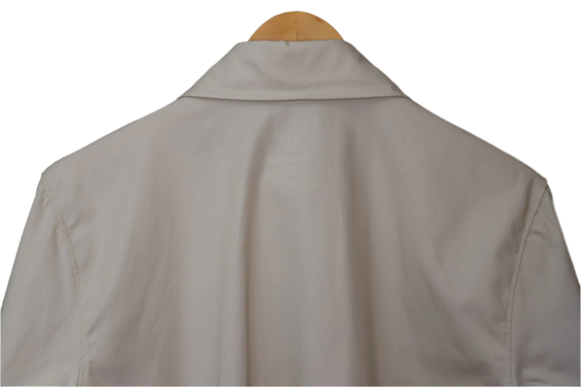 Light-colored shirt on a wooden hanger against a brown background
