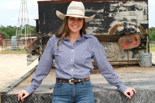 woman in cowgirl hat wearing gingham navy blue long sleeve shirt button down