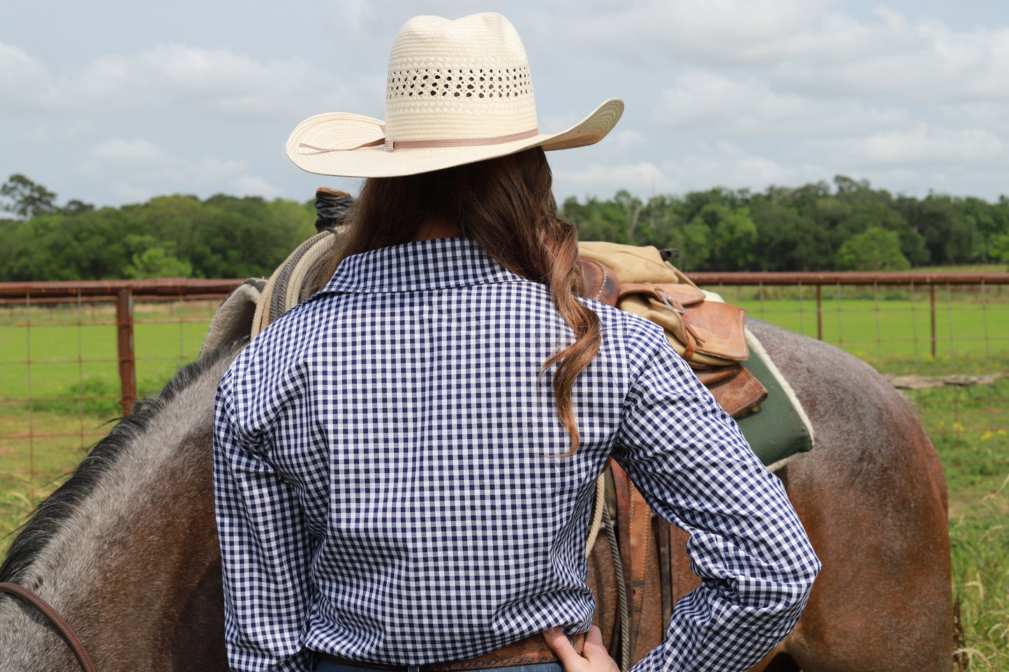 woman in cowgirl hat wearing gingham navy blue long sleeve shirt button down