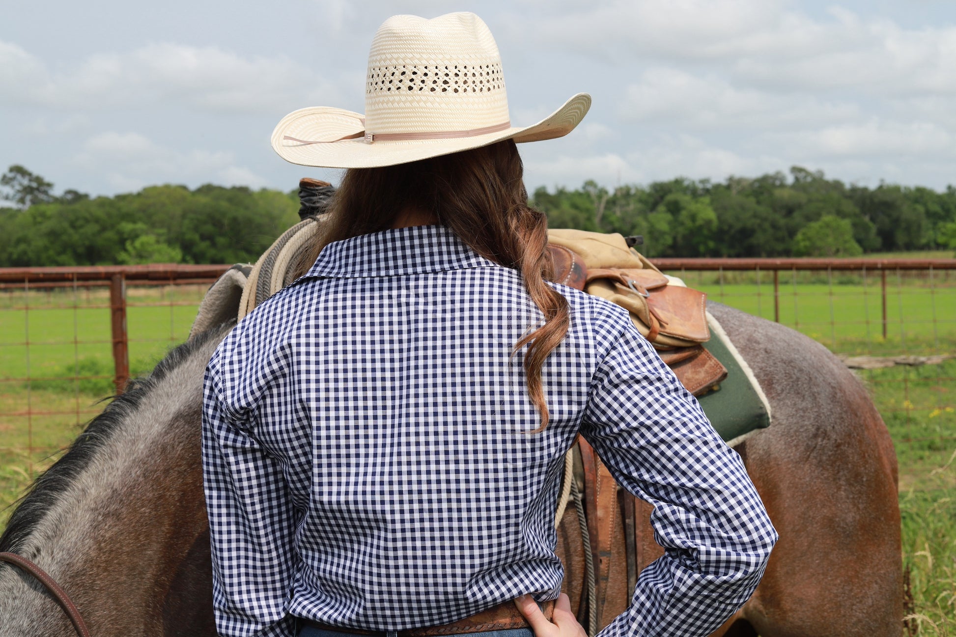 woman in cowgirl hat wearing gingham navy blue long sleeve shirt button down