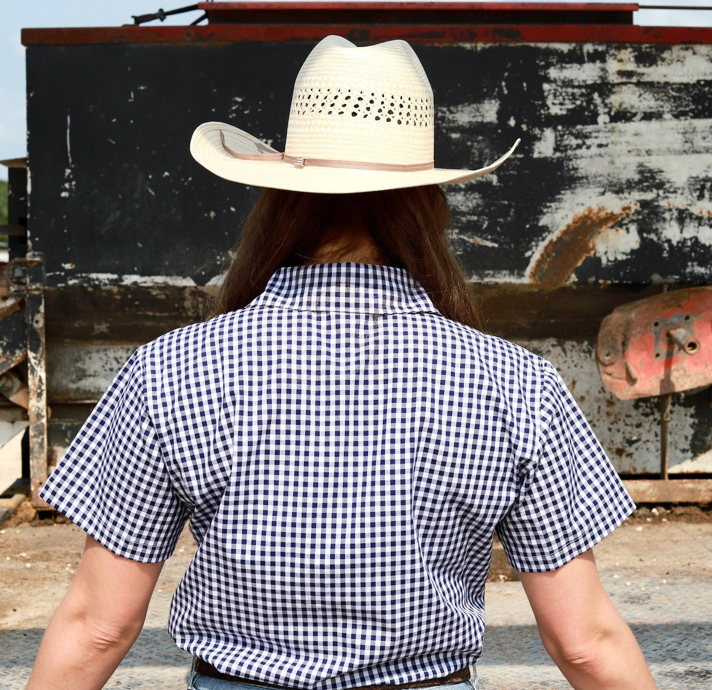 woman with cowgirl hat on standing in front of a feed truck